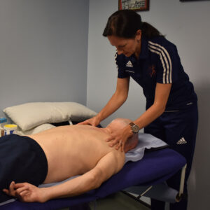 A physiotherapist at Hampden Sports Clinic providing hands on treatment to a client on a bed